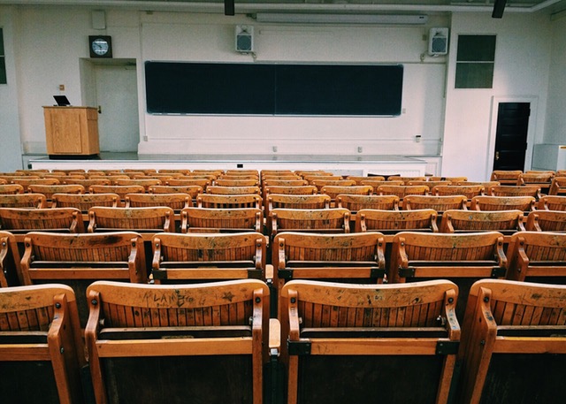 Aula con serie di sedie in legno con lavagna nera sul fondo